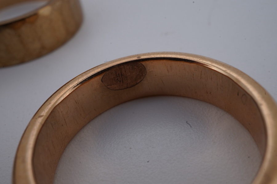 Four gold rings, comprising: a 22ct gold wedding band, size M, British assay marks, gross weight 3 grams; a 9ct gold band with a panelled finish, size N, British hallmarks, gross weight approximately 3.5 grams; a bicolou